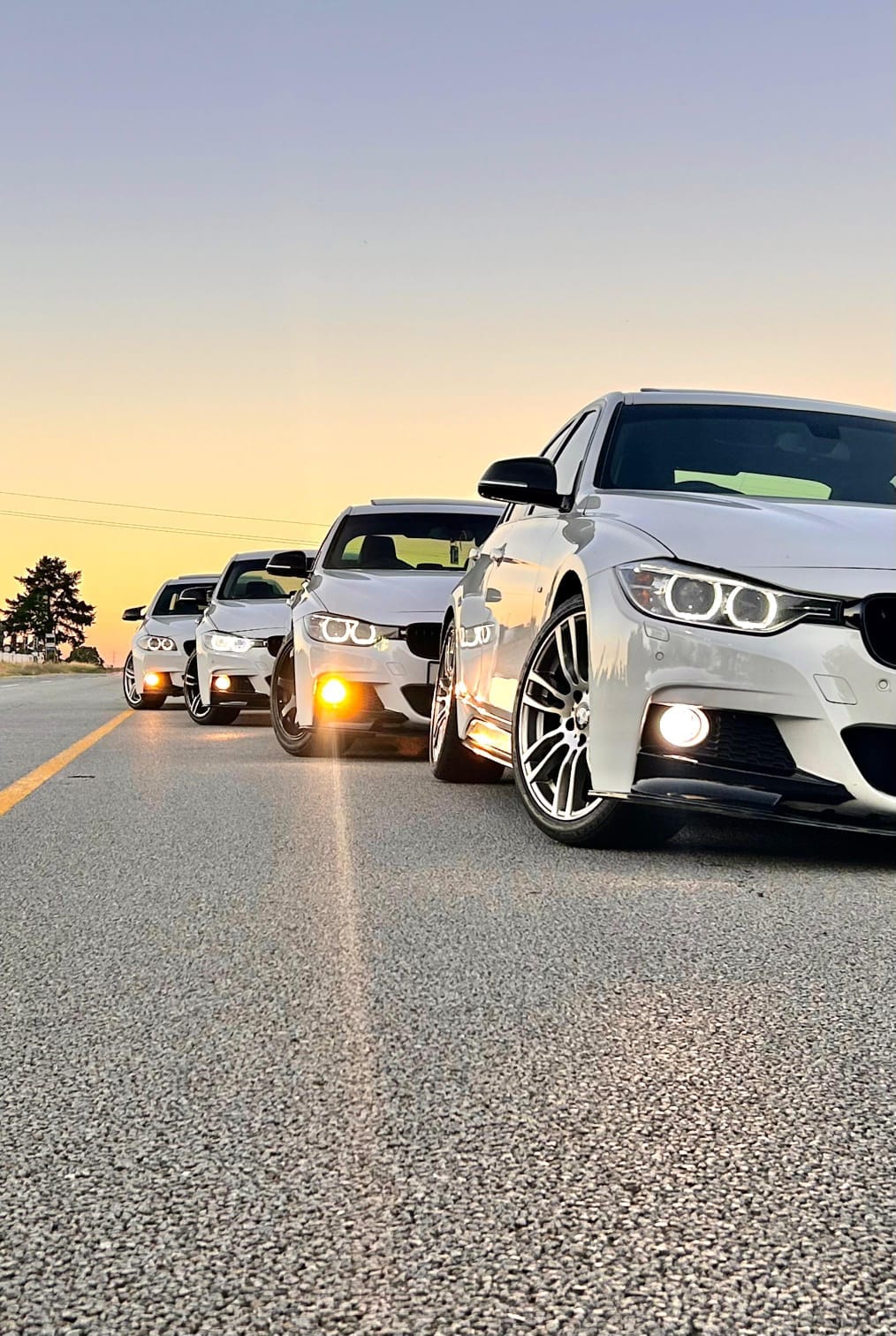 Four white BMWs in convoy on an open road at sunset outside Cape Town